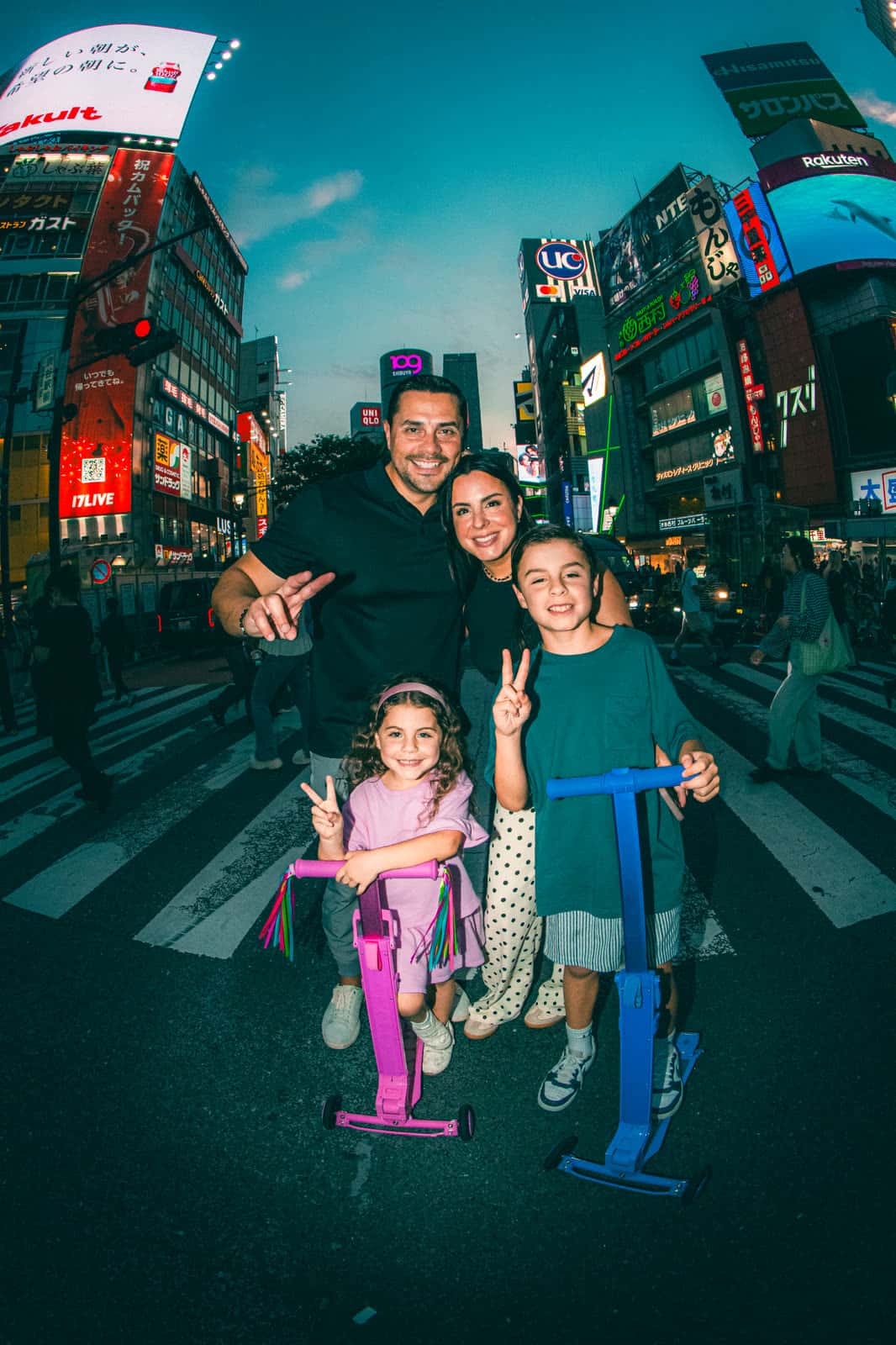 Family with two kids and scooters on a Tokyo crosswalk