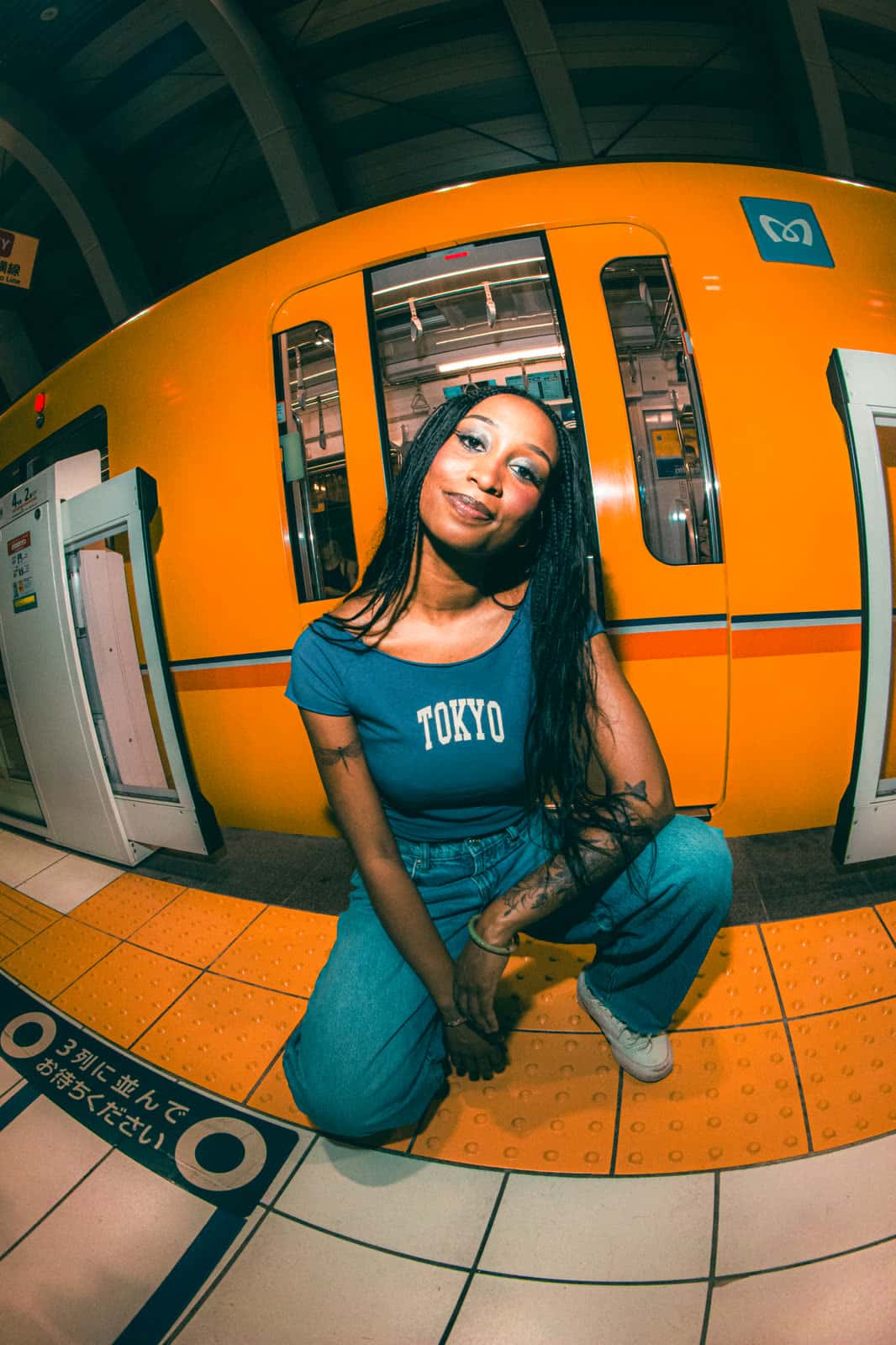 Woman kneeling beside an orange Tokyo subway train