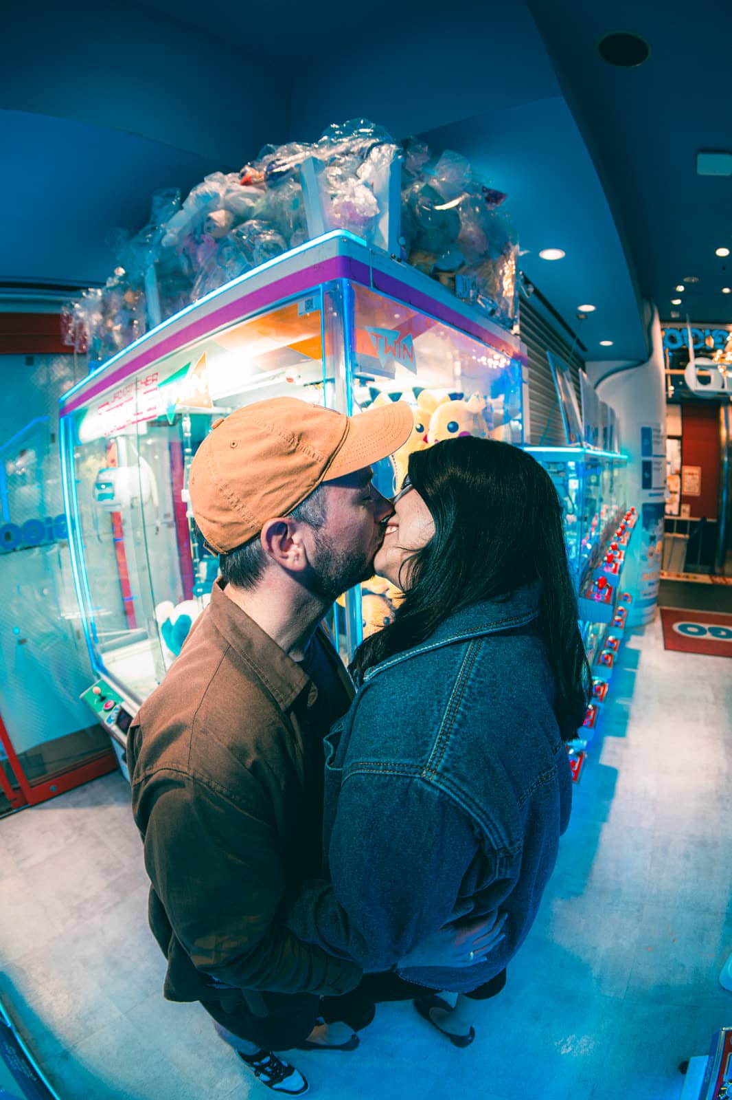 Couple kissing beside a claw machine in a Tokyo arcade