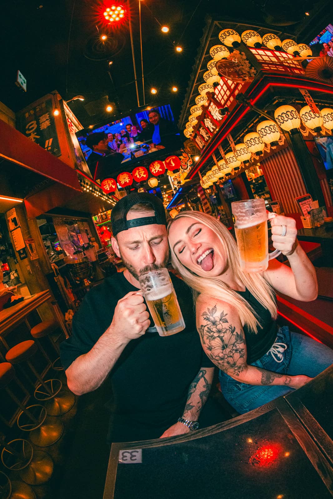 Couple toasting with beer in a lantern-lit izakaya alley