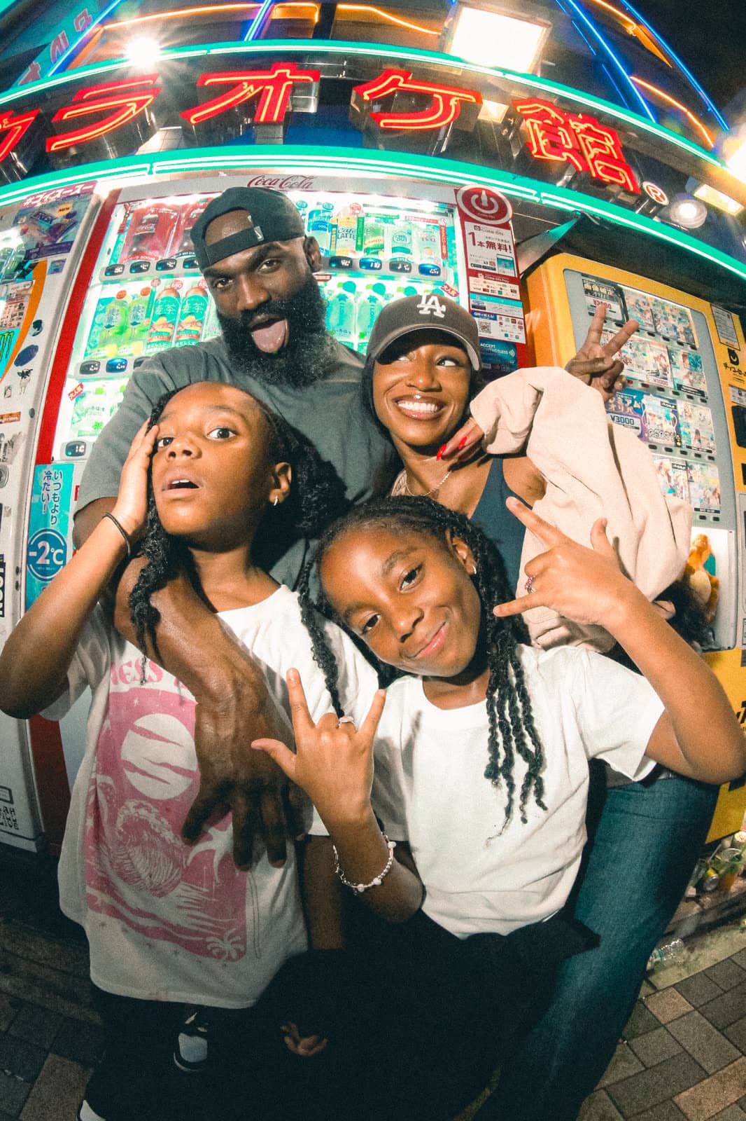 Family by a vending machine under neon lights at night