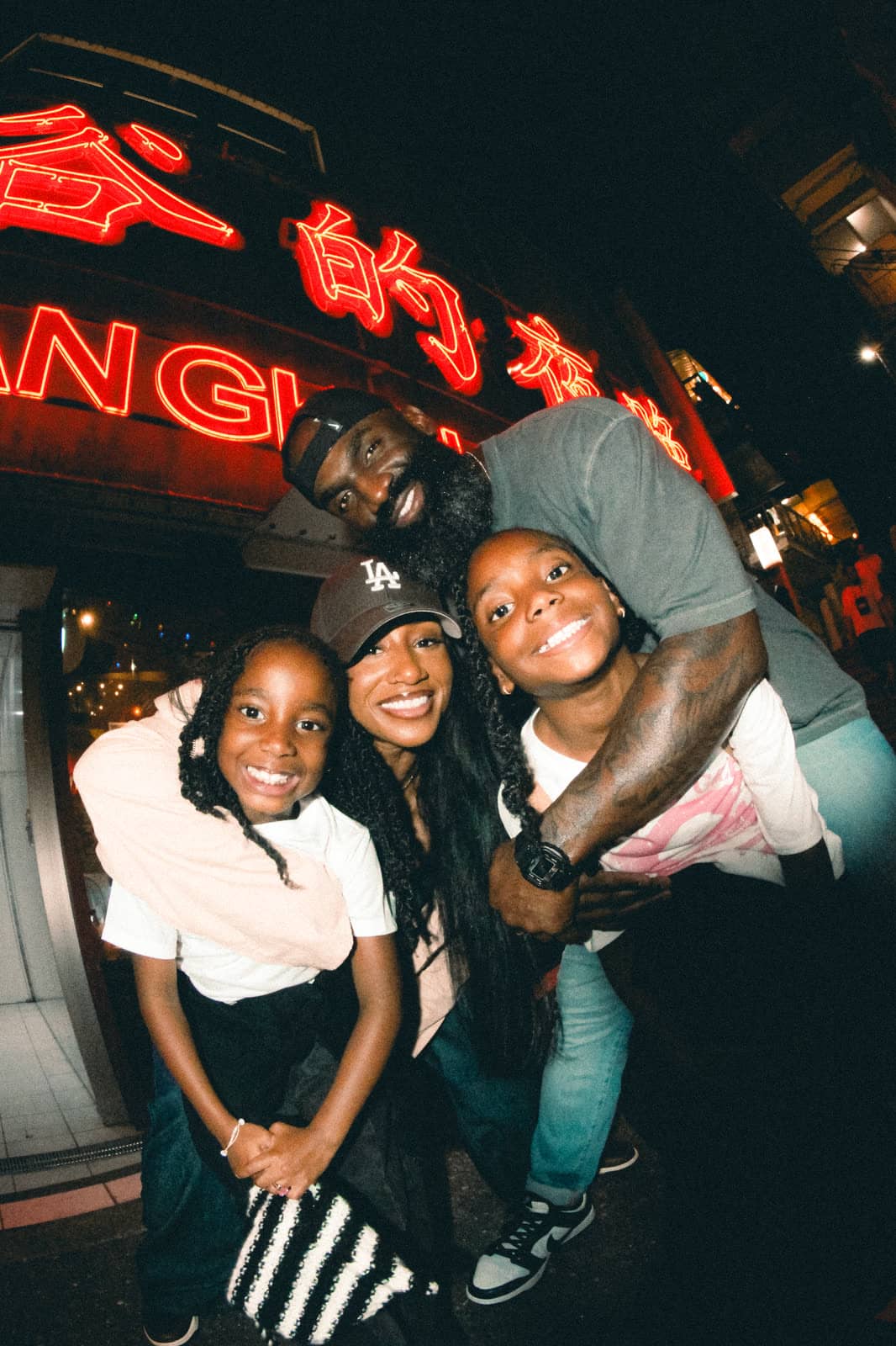 Family laughing together under a red neon sign