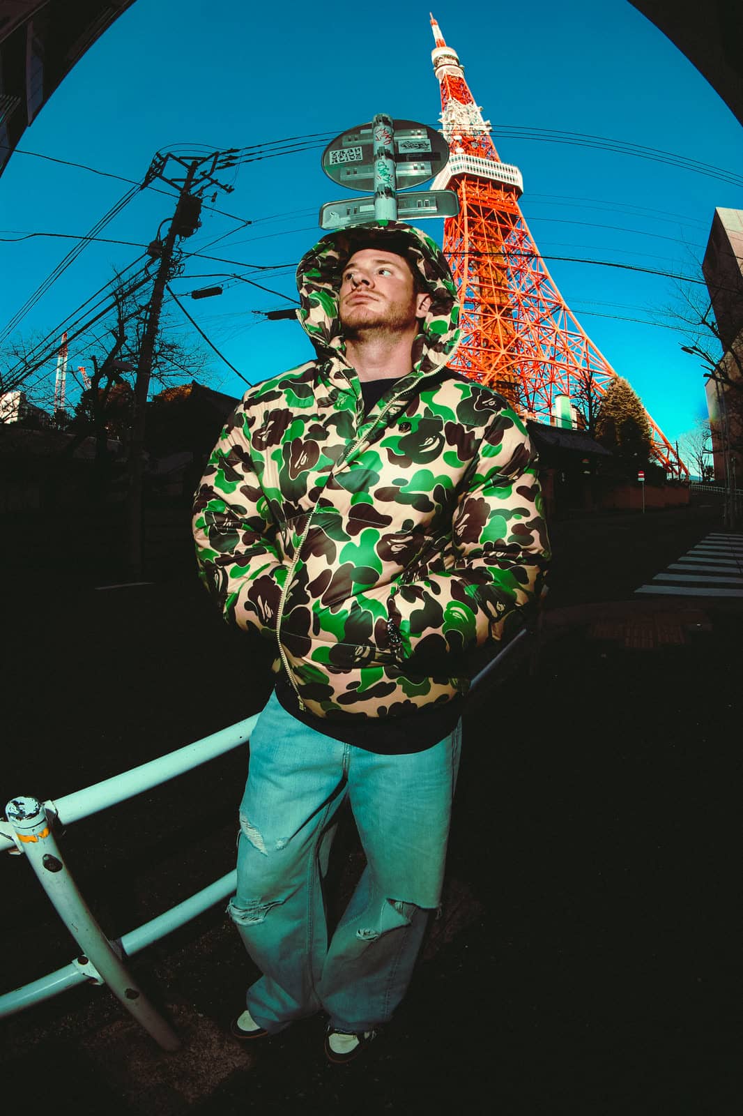 Man in a camouflage jacket below Tokyo Tower