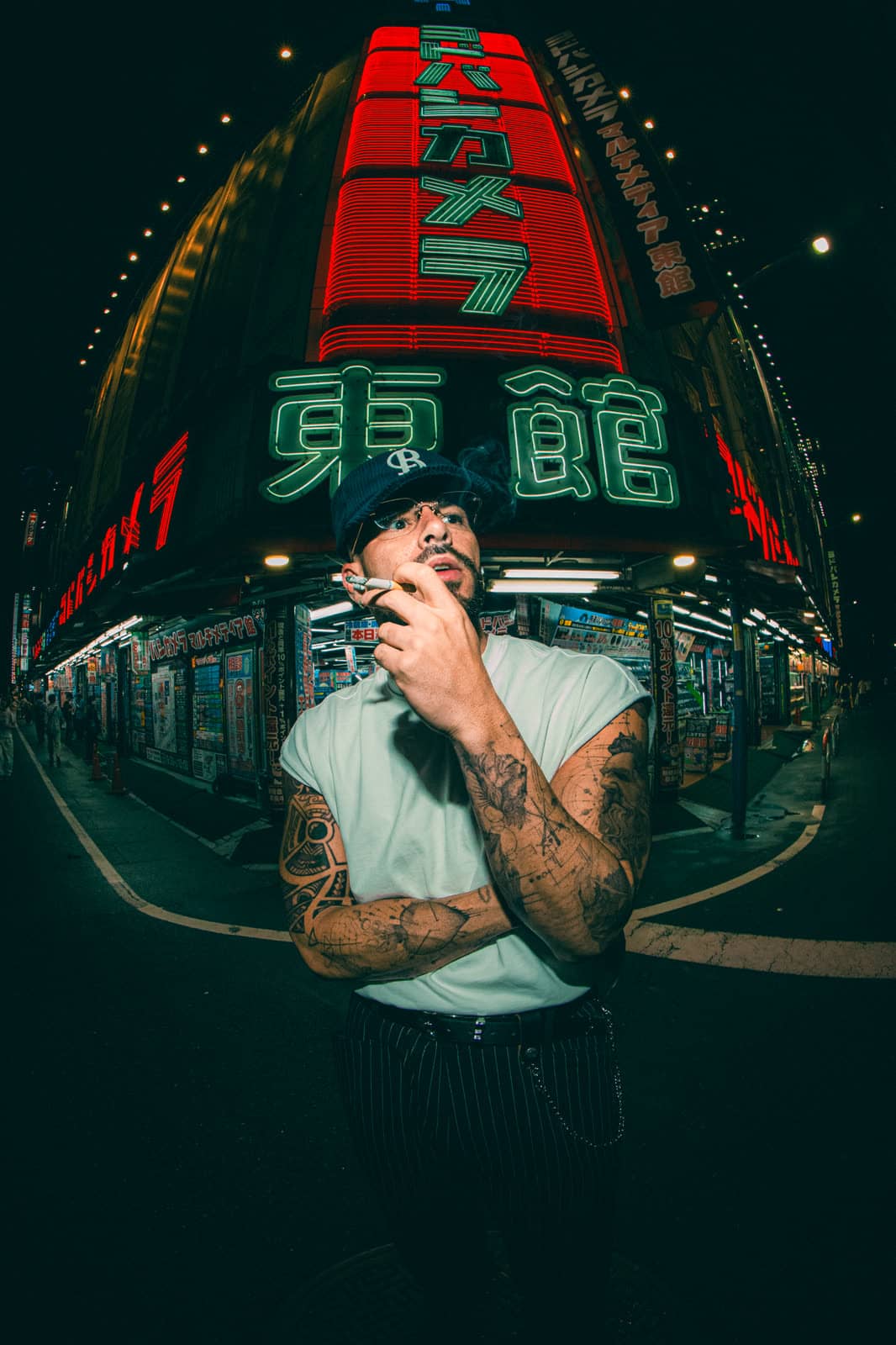 Man under a green neon store sign at night