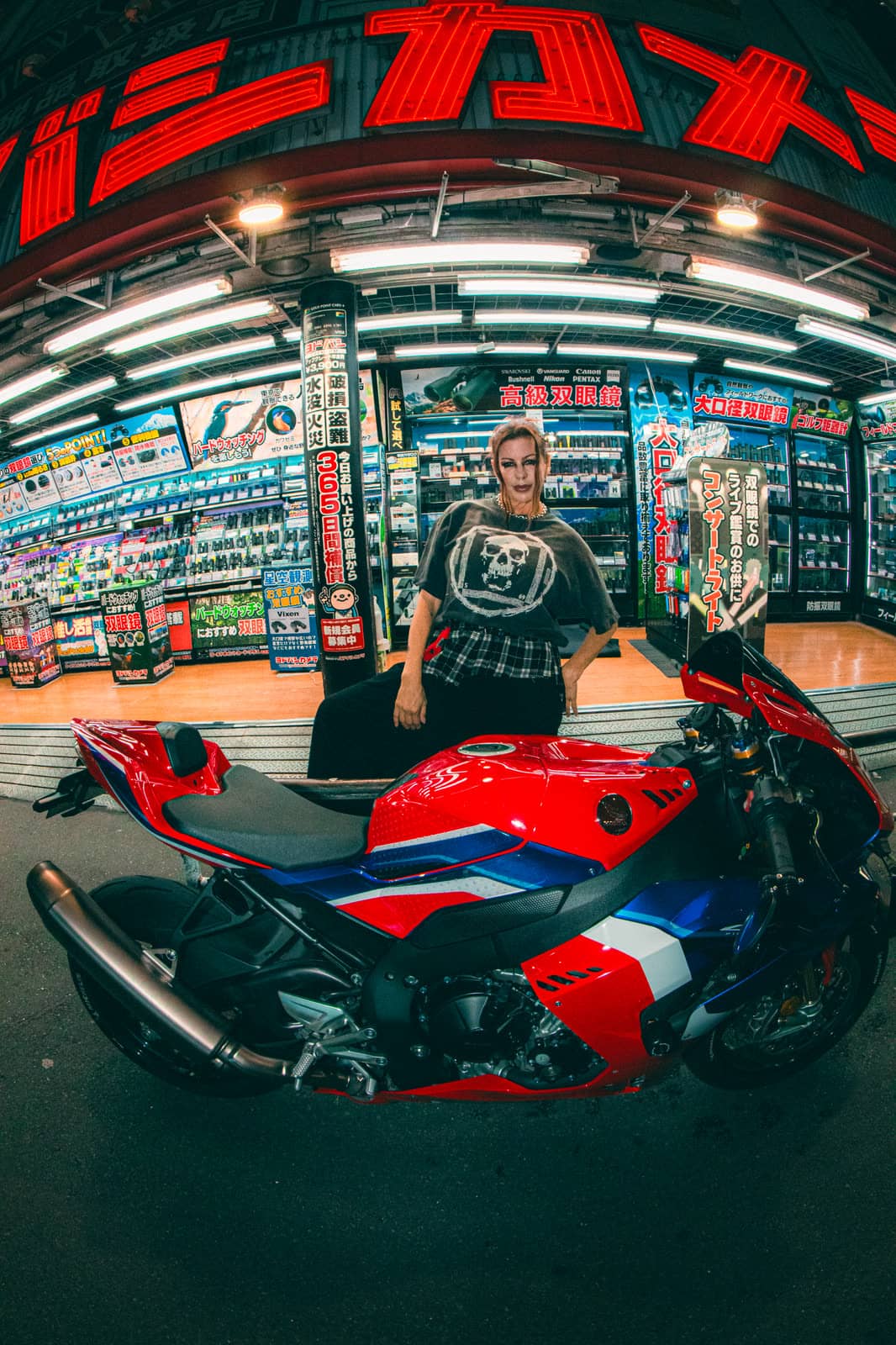 Man with a red motorcycle outside an electronics store