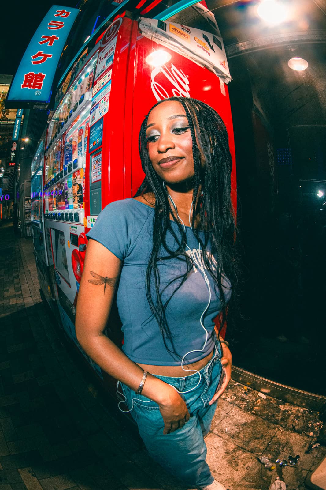 Woman beside a red vending machine at night